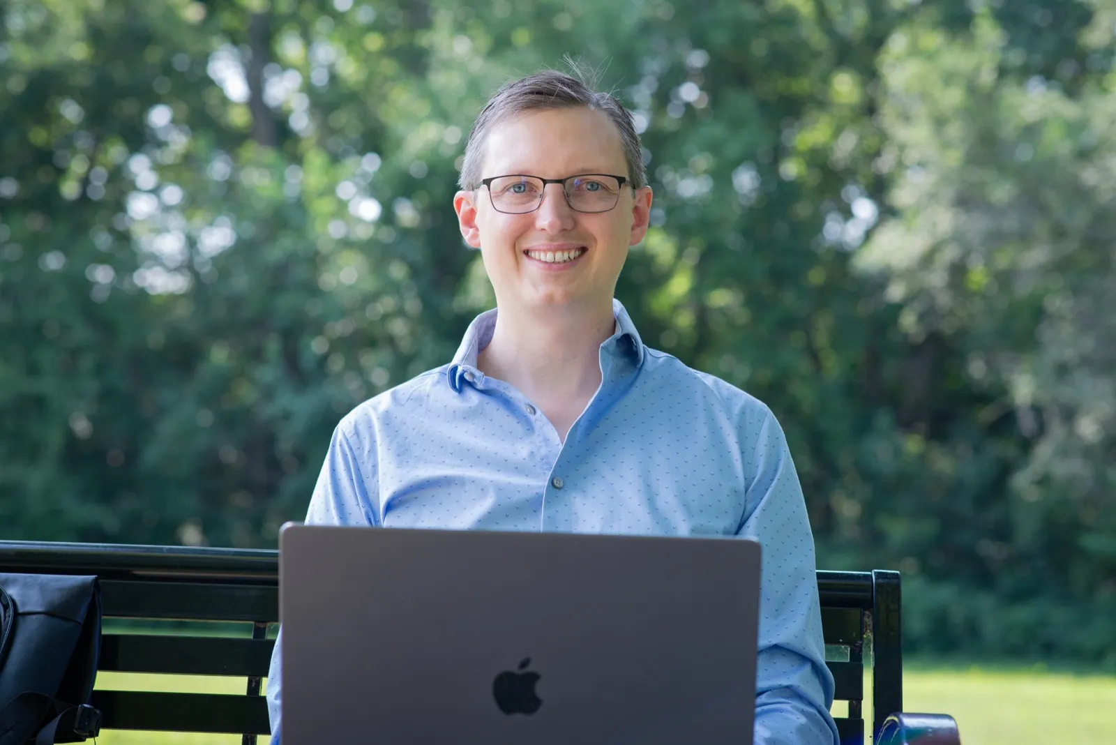 Georg Link smiling at the viewer over an open laptop, outdoors